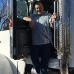 A driver stands in the door of a Liberty Sand & Gravel truck.